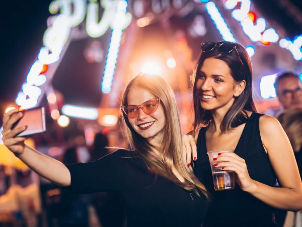 Two female friends friends taking a selfie in amusement park